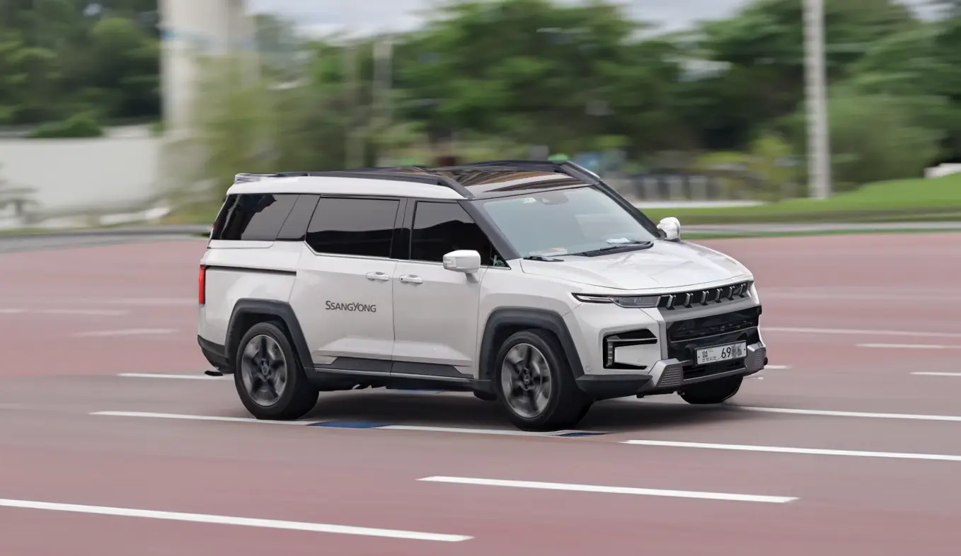 쌍용자동차 대형 SUV 토레스가 도로를 힘차게 주행하며, 세련된 흰색 차체와 블랙 루프가 현대적이고 강인한 느낌을 강조한다.