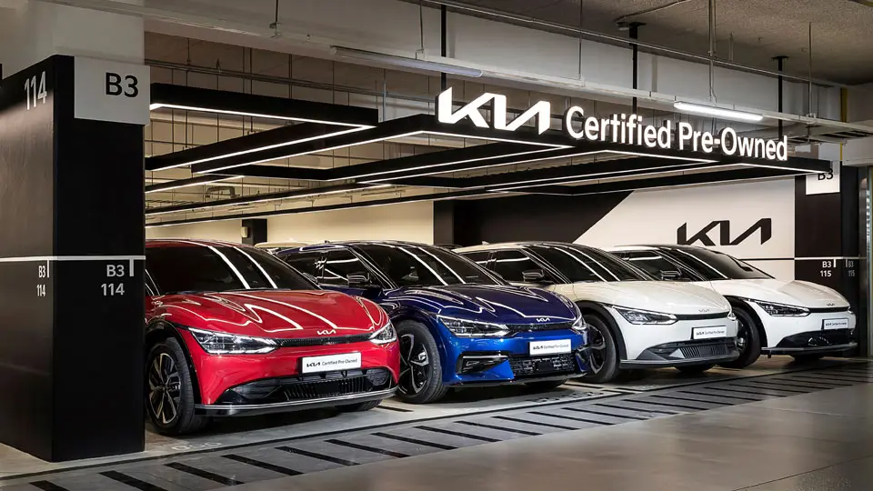 기아 인증 중고차 전시장에서 빨간색, 파란색, 흰색 등 다양한 EV6 전기차가 세련된 실내 조명 아래 가지런히 주차되어 있는 모습.