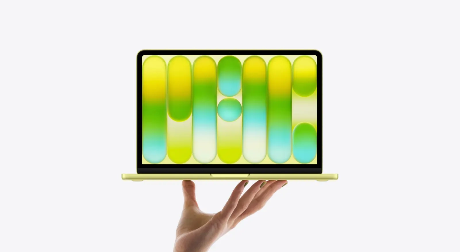 노란색 맥북 네오를 한 손으로 받치고 있으며, 화면에는 초록색과 노란색의 추상 그래픽이 선명하게 표현되어 현대적이고 세련된 분위기를 연출한다.