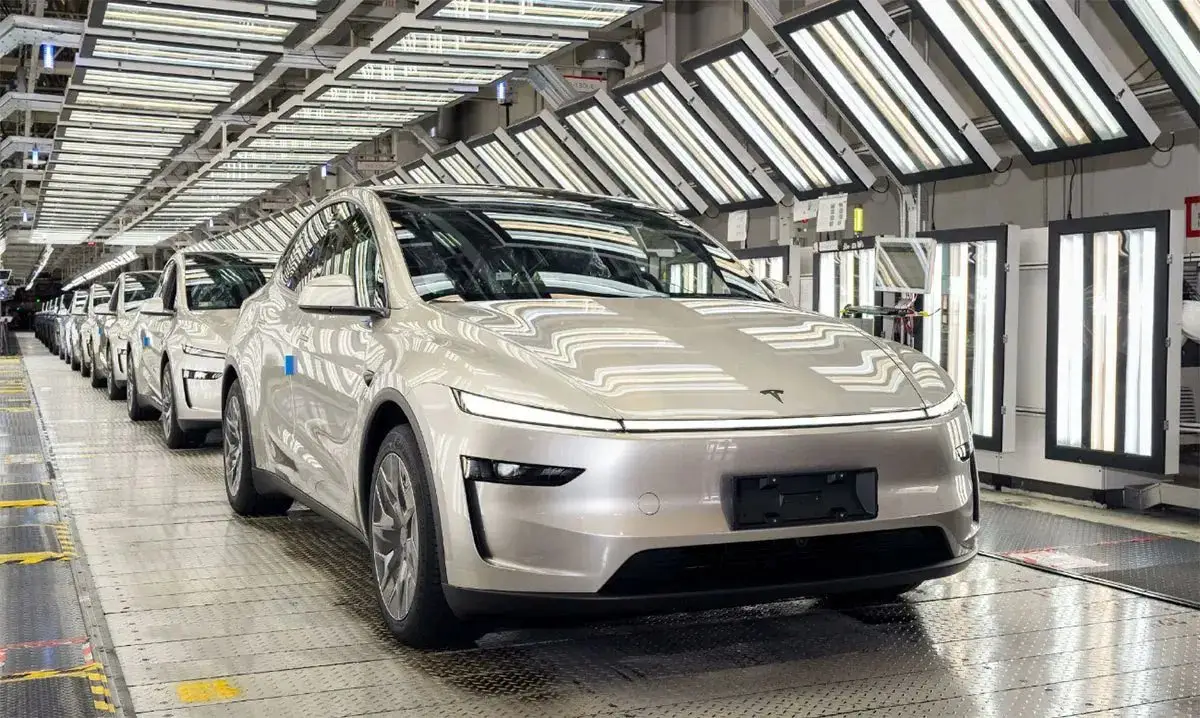 전기차 생산공장에서 최신 테슬라 자동차들이 조립 라인을 따라 정렬되어 완성도를 점검받고 있는 현대적인 제조 현장 모습.