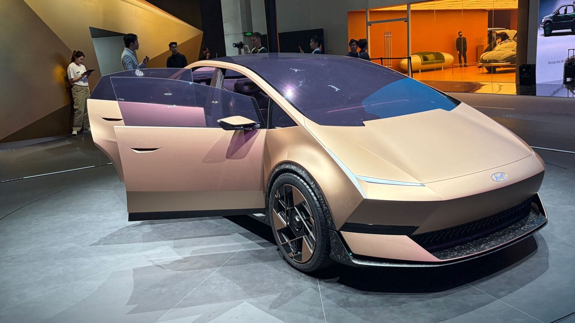 현대의 혁신적인 전기차 컨셉트 모델이 전시된 모습. 개방된 드라이브 도어와 미래지향적인 디자인이 특징이며, 배경에는 관람객들이 보인다.