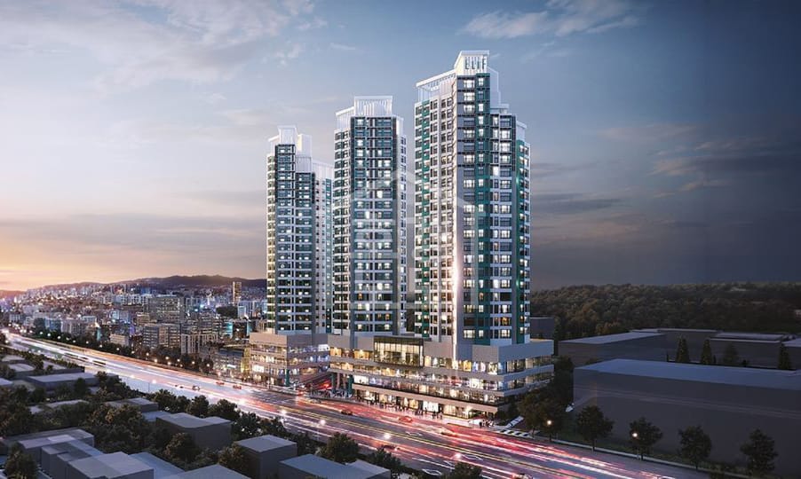 현대적인 고층 아파트 단지의 외관, 저녁 하늘 아래 조명이 반짝이는 모습. 도시의 풍경과 함께 도로에서 차량들이 지나가는 장면.