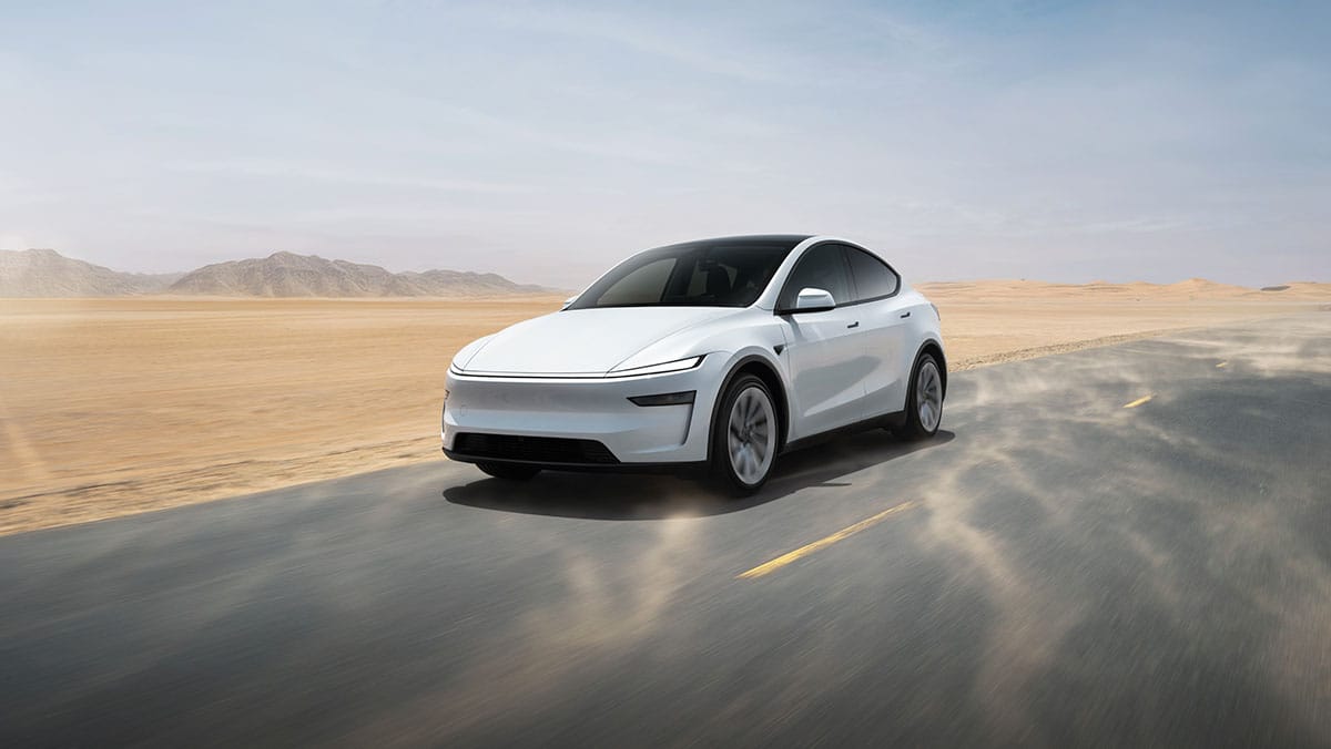 전경에서 주행 중인 흰색 전기 SUV, 현대적인 디자인과 매끄러운 라인이 특징이며, 사막 배경과 함께 먼지가 일어나는 모습.