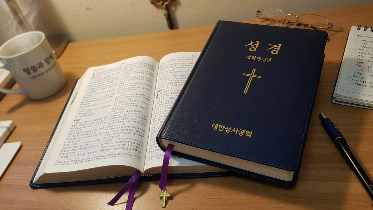 개역개정판 성경과 필기노트, 커피잔, 안경이 나무 책상 위에 정돈되어 있어 조용한 묵상과 성경 공부 분위기를 자아냄.