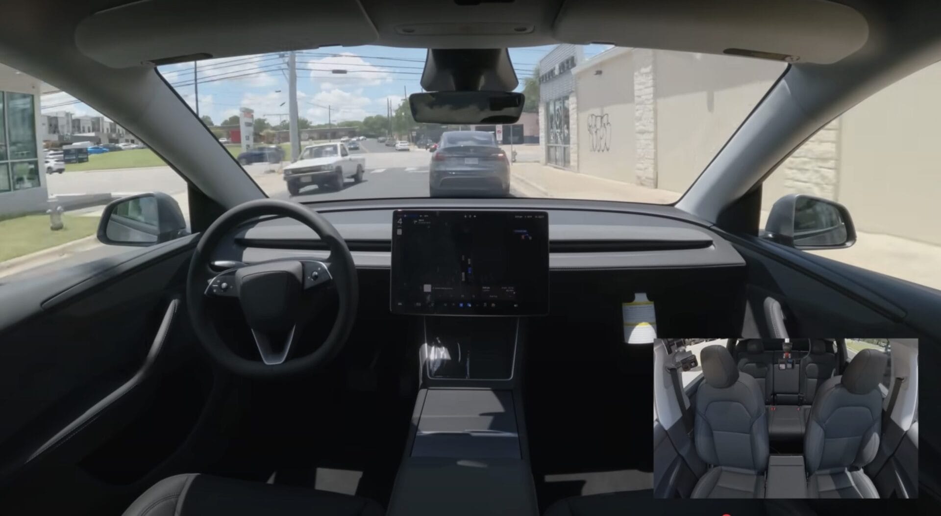 전방 도로가 보이는 전기차의 운전석 내부 모습, 대형 디스플레이에 내비게이션 정보가 표시되어 있으며, 차량 내부는 현대적인 디자인과 편안한 좌석이 특징입니다.