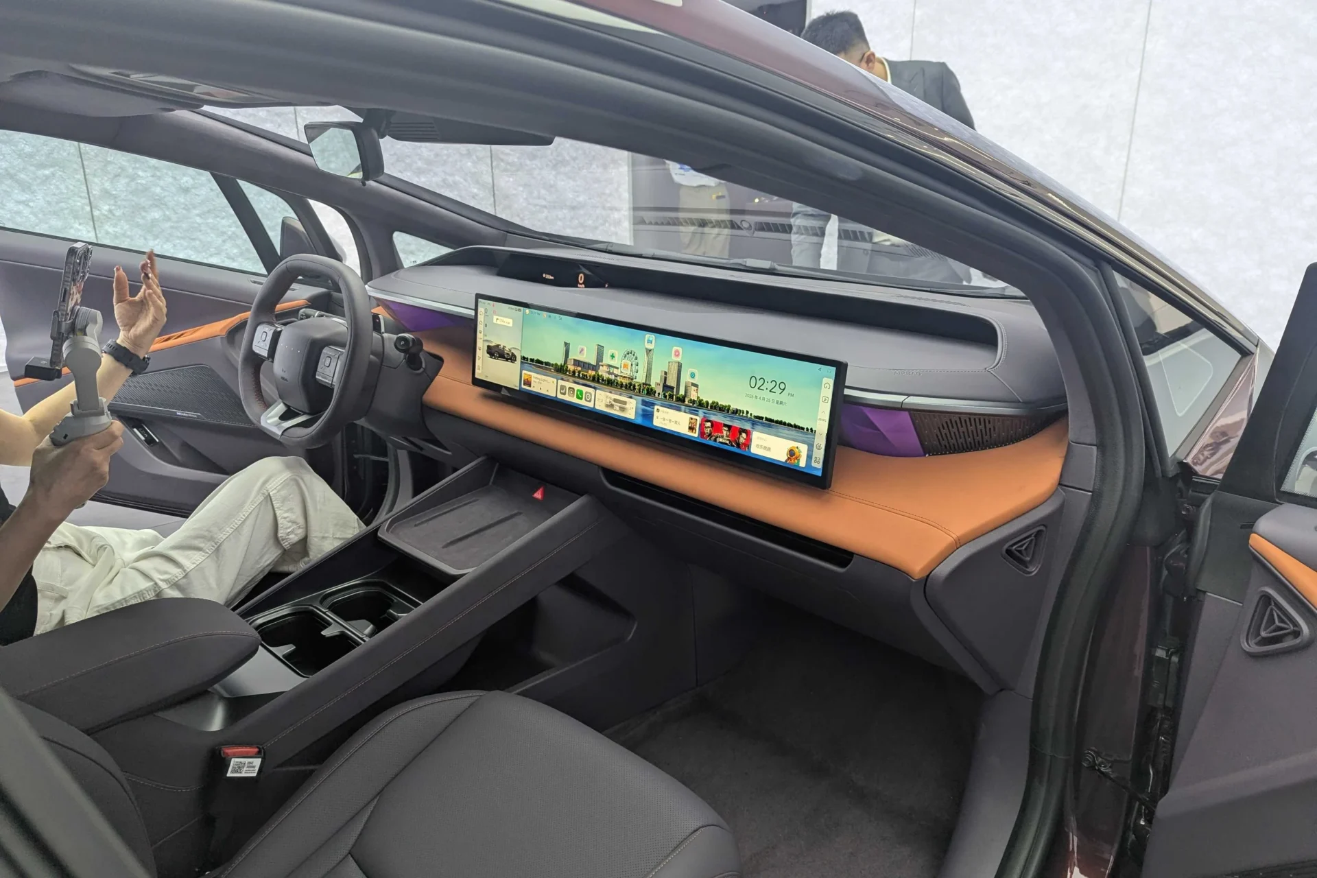 최신 전기차의 내부 모습, 대형 디스플레이와 현대적인 디자인이 특징인 실내. 운전대와 다양한 컨트롤이 배치되어 있으며, 중앙 콘솔에 컵 홀더가 위치해 있음.