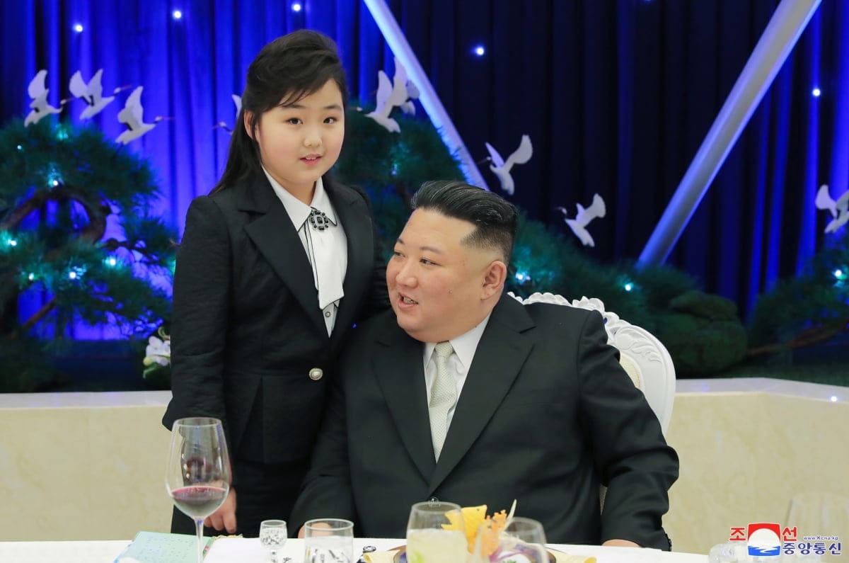 김정은과 그의 딸이 함께 앉아 있는 모습, 고급스러운 만찬 테이블 배경, 화려한 장식과 조명이 돋보이는 장면.