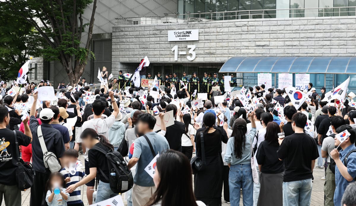 대규모 시위가 열리고 있는 모습으로, 참가자들이 태극기를 들고 있으며, 경찰이 시위 현장을 지키고 있다. 다양한 연령대의 사람들이 모여 있고, 건물 앞에는 여러 개의 표지판이 세워져 있다.