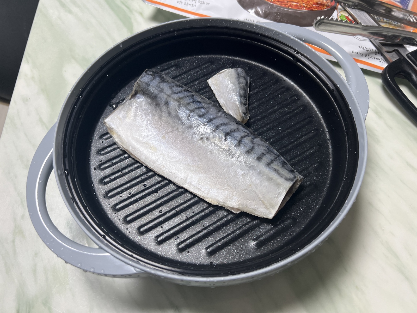 전자레인지용 그릴에 놓인 고등어 조각, 간편한 조리를 위한 준비 상태.